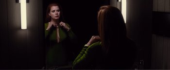 Movie still from “Nocturnal Animals” (2016), directed by Tom Ford – A woman looking in the mirror while tying a bow tie; Medium shot, Over the shoulder angle