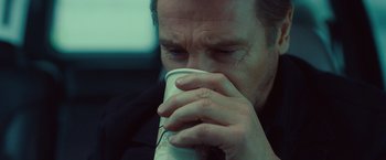 Movie still from “Non-Stop” (2014), directed by Jaume Collet-Serra – A person drinking a cup of coffee; Close Up shot, Low angle