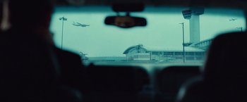 Movie still from “Non-Stop” (2014), directed by Jaume Collet-Serra – A view from a car of an airport with a plane taking off in the background; Extreme Wide shot, Over the shoulder angle