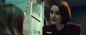 Movie still from “Non-Stop” (2014), directed by Jaume Collet-Serra – A woman in a red jacket standing next to a door; Close Up shot, Over the shoulder angle