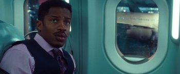 Movie still from “Non-Stop” (2014), directed by Jaume Collet-Serra – A man in a suit and tie on a train looking out the window; Close Up shot, Over the shoulder angle