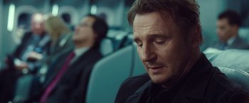 Movie still from “Non-Stop” (2014), directed by Jaume Collet-Serra – A man sitting on a train with a man in the background; Close Up shot, Over the shoulder angle