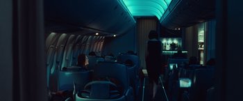 Movie still from “Non-Stop” (2014), directed by Jaume Collet-Serra – A woman walking down the aisle of an airplane at night; Wide shot, Over the shoulder angle