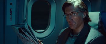 Movie still from “Non-Stop” (2014), directed by Jaume Collet-Serra – A man sitting on a plane holding an umbrella; Close Up shot, Over the shoulder angle