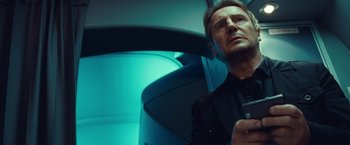 Movie still from “Non-Stop” (2014), directed by Jaume Collet-Serra – A man in a black shirt is sitting in a car; Close Up shot, Low angle