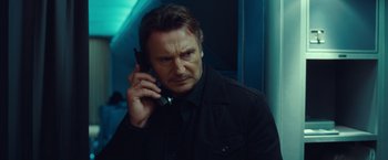 Movie still from “Non-Stop” (2014), directed by Jaume Collet-Serra – A man holding a cell phone up to his ear; Close Up shot, Low angle