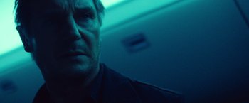 Movie still from “Non-Stop” (2014), directed by Jaume Collet-Serra – A man's face in a dark room; Close Up shot, Low angle