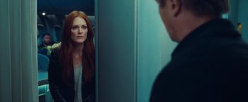 Movie still from “Non-Stop” (2014), directed by Jaume Collet-Serra – A woman standing in front of a bathroom mirror; Close Up shot, Over the shoulder angle
