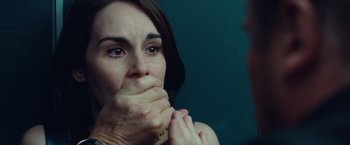 Movie still from “Non-Stop” (2014), directed by Jaume Collet-Serra – A person with their hands over their mouth; Close Up shot, Over the shoulder angle