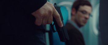 Movie still from “Non-Stop” (2014), directed by Jaume Collet-Serra – A person holding a gun in their hand; Close Up shot, Over the shoulder angle