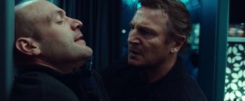 Movie still from “Non-Stop” (2014), directed by Jaume Collet-Serra – Two men are looking at each other in a dark room; Close Up shot, Over the shoulder angle