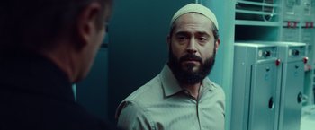 Movie still from “Non-Stop” (2014), directed by Jaume Collet-Serra – A man with a beard wearing a white hat looking in a mirror; Close Up shot, Over the shoulder angle