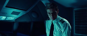 Movie still from “Non-Stop” (2014), directed by Jaume Collet-Serra – A man in a uniform is standing in the dark; Medium shot, Low angle