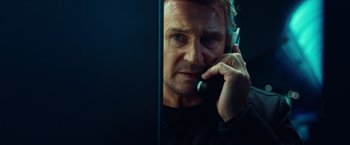 Movie still from “Non-Stop” (2014), directed by Jaume Collet-Serra – A man talking on a cell phone in front of a computer screen; Close Up shot, Low angle