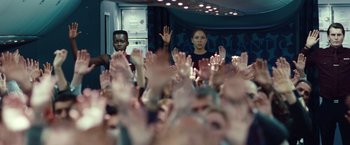 Movie still from “Non-Stop” (2014), directed by Jaume Collet-Serra – A group of people raising their hands in front of a crowd; Medium shot, High angle