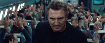 Movie still from “Non-Stop” (2014), directed by Jaume Collet-Serra – Liam neeson in front of a crowd; Close Up shot, Over the shoulder angle