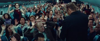 Movie still from “Non-Stop” (2014), directed by Jaume Collet-Serra – A crowd of people sitting and standing in a room; Wide shot, High angle