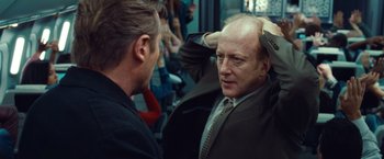 Movie still from “Non-Stop” (2014), directed by Jaume Collet-Serra – A man in a suit and tie talking to another man in a suit and tie; Close Up shot, Over the shoulder angle