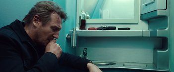 Movie still from “Non-Stop” (2014), directed by Jaume Collet-Serra – A man sitting in front of a sink in a bathroom; Close Up shot, Low angle