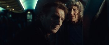 Movie still from “Non-Stop” (2014), directed by Jaume Collet-Serra – A man and a woman standing next to each other; Close Up shot, Low angle