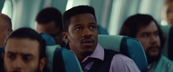 Movie still from “Non-Stop” (2014), directed by Jaume Collet-Serra – A man sitting on top of an airplane looking off to his right; Close Up shot, Low angle