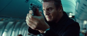 Movie still from “Non-Stop” (2014), directed by Jaume Collet-Serra – A person holding a gun; Close Up shot, Low angle