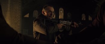 Movie still from “Mission: Impossible - Fallout” (2018), directed by Christopher McQuarrie – A man holding a gun while standing in a dark room; Medium shot, Low angle