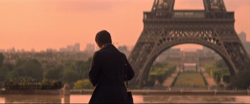 Movie still from “Mission: Impossible - Fallout” (2018), directed by Christopher McQuarrie – A woman standing in front of the eiffel tower at sunset; Extreme Wide shot, Low angle