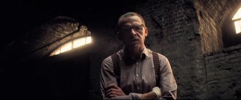 Movie still from “Mission: Impossible - Fallout” (2018), directed by Christopher McQuarrie – A man with glasses standing in front of a brick wall; Medium shot, Low angle