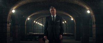 Movie still from “Mission: Impossible - Fallout” (2018), directed by Christopher McQuarrie – A man in a suit and tie standing in a dark room; Medium shot, Low angle