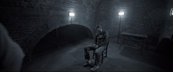 Movie still from “Mission: Impossible - Fallout” (2018), directed by Christopher McQuarrie – A man sitting on a chair in a dark room; Wide shot, High angle