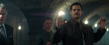 Movie still from “Mission: Impossible - Fallout” (2018), directed by Christopher McQuarrie – A man holding a light in his hand while standing next to another man; Medium shot, Over the shoulder angle