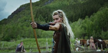 A woman is holding a bow and arrow in her hands