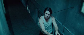 Movie still from “Mission: Impossible - Ghost Protocol” (2011), directed by Brad Bird – A man in a white tank top leaning on a railing; Medium shot, Low angle