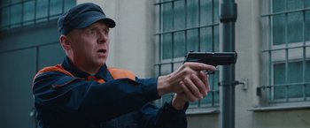 Movie still from “Mission: Impossible - Ghost Protocol” (2011), directed by Brad Bird – A man in an orange and blue uniform holding a gun; Medium shot, Low angle