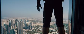 Movie still from “Mission: Impossible - Ghost Protocol” (2011), directed by Brad Bird – A man standing on top of a building looking down at a city; Wide shot, Low angle