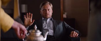 Movie still from “Mission: Impossible - Ghost Protocol” (2011), directed by Brad Bird – A man sitting at a table in front of a tea pot; Medium shot, Low angle