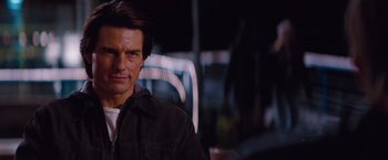 Movie still from “Mission: Impossible - Ghost Protocol” (2011), directed by Brad Bird – A man in a black jacket standing in front of blurry lights; Close Up shot, Over the shoulder angle