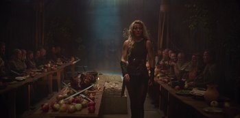 A woman in black shirt holding a sword in a room full of food