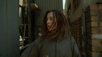 Movie still from “Oats Studios” (2017), directed by Neill Blomkamp – A woman with dreadlocks standing in the street; Close Up shot, Over the shoulder angle