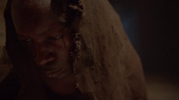 Movie still from “Oats Studios” (2017), directed by Neill Blomkamp – A man with a long dreadlocks is looking at the camera; Extreme Close Up shot, High angle