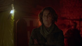 Movie still from “Oats Studios” (2017), directed by Neill Blomkamp – A woman standing in the dark with her arms crossed; Close Up shot, Over the shoulder angle