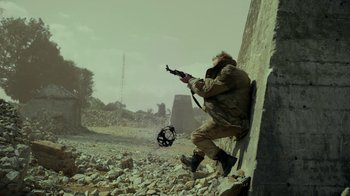 Movie still from “Oats Studios” (2017), directed by Neill Blomkamp – A man with a gun in his hand is leaning on a wall; Wide shot, Low angle