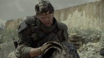 Movie still from “Oats Studios” (2017), directed by Neill Blomkamp – A man wearing a helmet and holding something; Medium shot, Over the shoulder angle