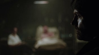 Movie still from “Oats Studios” (2017), directed by Neill Blomkamp – A man standing in front of a bed in a dark room; Close Up shot, Over the shoulder angle