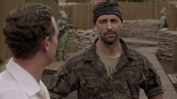Movie still from “Oats Studios” (2017), directed by Neill Blomkamp – A man in a camouflage shirt is talking to another man; Close Up shot, Over the shoulder angle