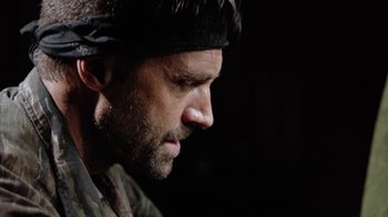 Movie still from “Oats Studios” (2017), directed by Neill Blomkamp – A person wearing a hat; Close Up shot, Over the shoulder angle