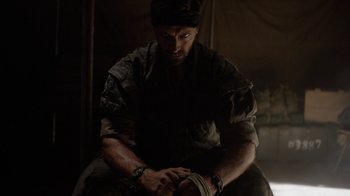 Movie still from “Oats Studios” (2017), directed by Neill Blomkamp – A man sitting in a dark room holding a pair of handcuffs; Close Up shot, Low angle