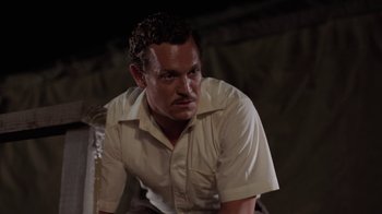 Movie still from “Oats Studios” (2017), directed by Neill Blomkamp – A man in a white dress shirt is sitting down; Medium shot, Low angle