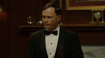 Movie still from “Oats Studios” (2017), directed by Neill Blomkamp – A man wearing a tuxedo and a bow tie; Close Up shot, Over the shoulder angle